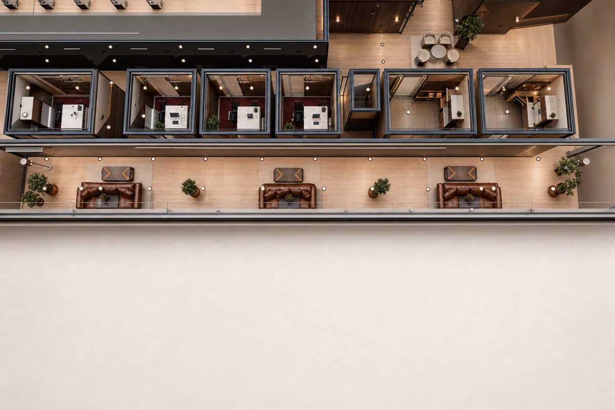 The OpenAGI lounge: low seating around a coffee table, warm lamps, tall greenery, and glass walls onto the office floor.